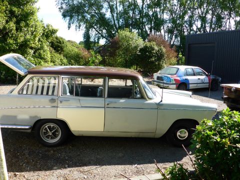 1962 MG B - A light-colored station wagon with a brown roof is parked outdoors, with its rear hatch open. Another vehicle is visible behind it.