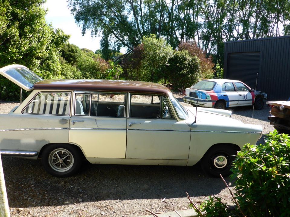 Station wagon with brown roof, side view. Another car with colorful paint is parked behind
