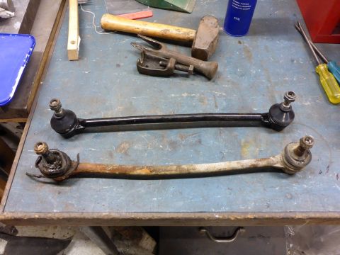 1962 MG B - A comparison of a new suspension rod next to a heavily corroded old one, with various tools scattered around.