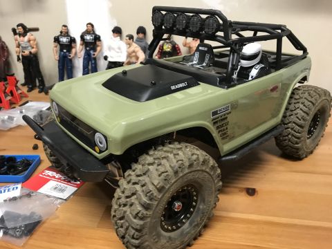 1989 Ford Bronco - A remote-controlled rock crawler vehicle is shown with various action figures in the background.
