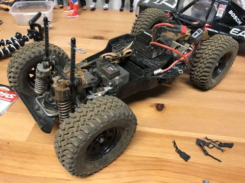 1989 Ford Bronco - The chassis of a remote control car sits on a wooden surface, showing its internal components and suspension system.