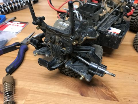 1989 Ford Bronco - Close-up of a disassembled RC car's rear suspension system on a wooden surface.