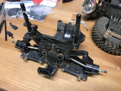 1989 Ford Bronco - Close-up of disassembled RC car suspension components and a tire, with packaging in the background.
