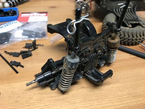 1989 Ford Bronco - Close-up of RC car suspension parts and drivetrain components laid out on a workbench.