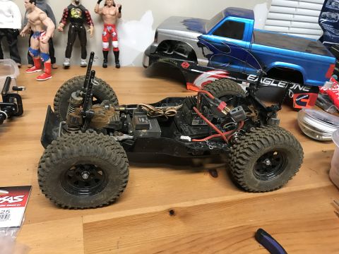1989 Ford Bronco - RC car chassis and a toy truck body are on a wooden surface, with action figures in the background.