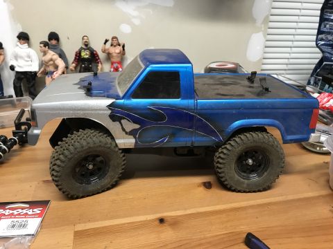 1989 Ford Bronco - RC truck body with custom paint and off-road tires sits on a wooden surface.