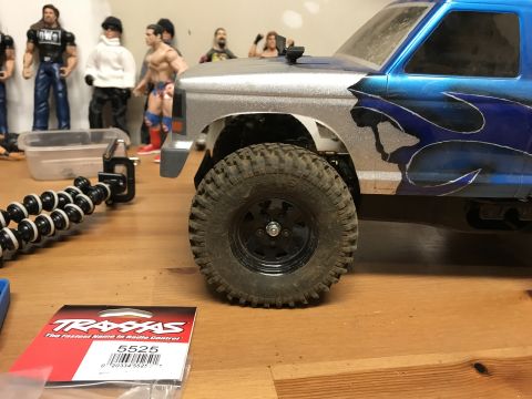 1989 Ford Bronco - A remote control truck is shown with a custom flame paint job, sitting on a wooden surface.