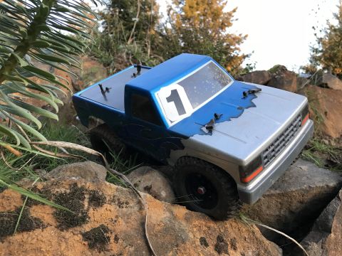 1989 Ford Bronco - A toy truck navigates a rocky terrain, its blue and silver paint job showing some wear.