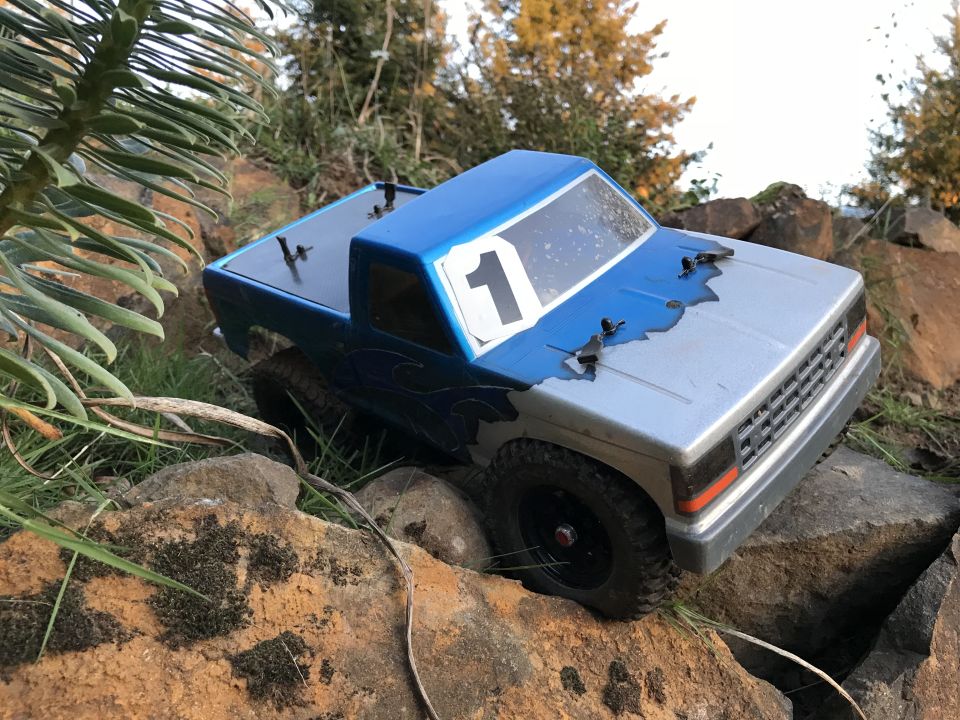 Blue and silver toy truck with number 1 on the door, on rocks