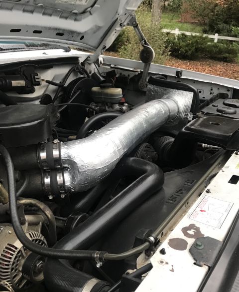 1995 Ford Bronco - Engine bay of a 1995 Ford Bronco, a custom intake system with silver-wrapped tubing and visible hoses.