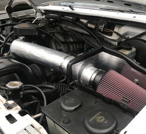 1995 Ford Bronco - Aftermarket air intake system installed in an engine bay.