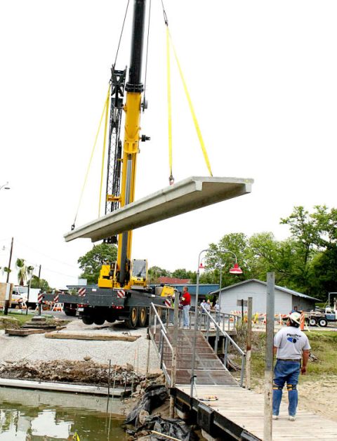 1979 Ford Ranchero - A large crane lifts a concrete slab as construction work takes place near a body of water and a wooden dock.