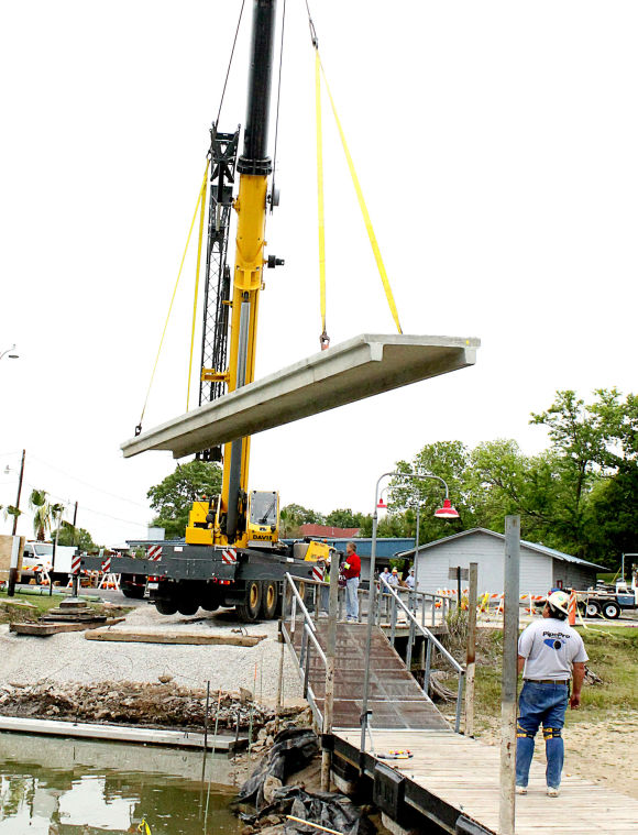 Crane lifting concrete slab over water and a dock