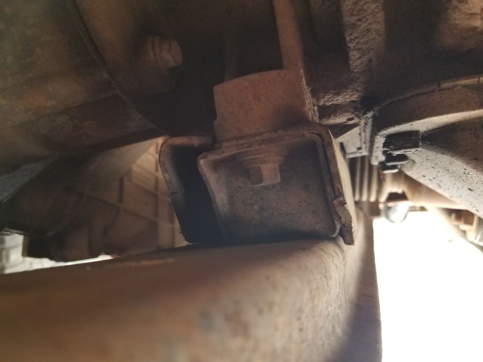 Close-up of a vehicle's engine mount, showing rust and wear