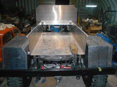 1992 Ford Bronco - The rear view of a custom-built vehicle, likely a truck or off-road vehicle, shows a metal bed and rear fenders. The vehicle is in a worksh…