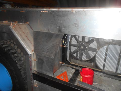 1992 Ford Bronco - A custom aluminum body is being fabricated around the front wheel well and radiator assembly of a vehicle. Visible components include a tir…