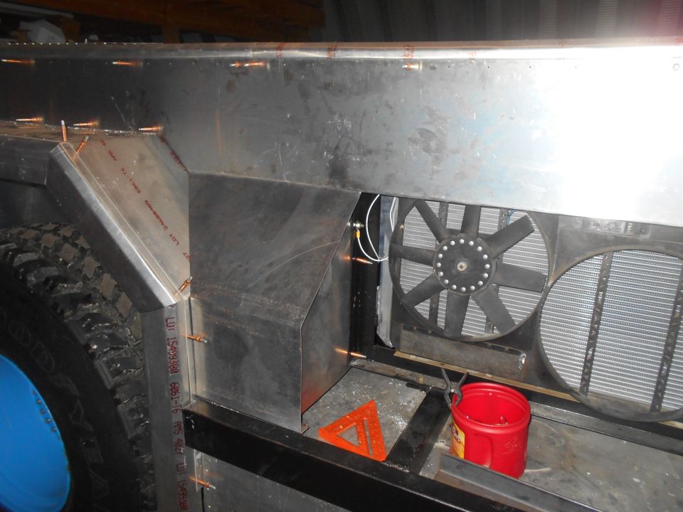 Custom aluminum body fabrication around vehicle tire and radiator.