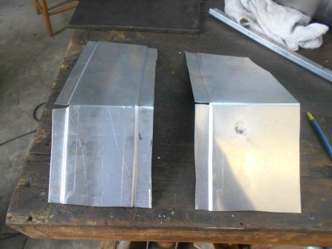 1992 Ford Bronco - Two custom-fabricated sheet metal pieces are laid out on a wooden workbench. The pieces appear to be parts of a vehicle's body, possibly fo…