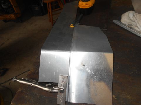 1992 Ford Bronco - A metal fabrication project is underway on a wooden workbench. Two pieces of bent sheet metal are positioned next to each other, with a loc…
