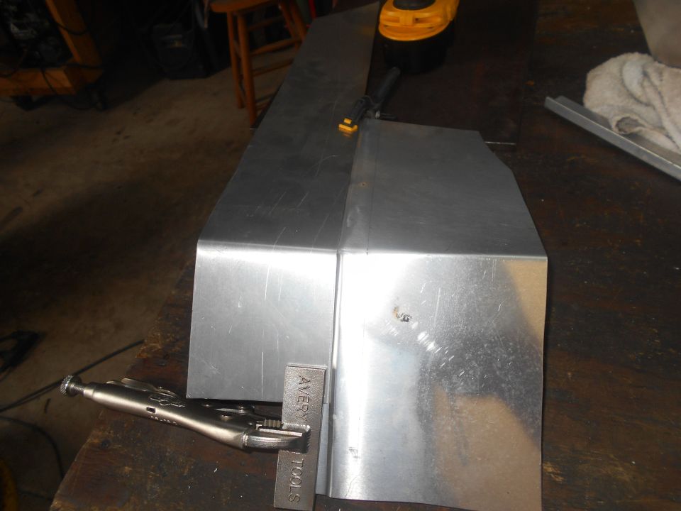 Sheet metal pieces on a workbench with a locking plier.