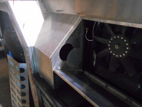 1992 Ford Bronco - A close-up view of the internal components of a vehicle, showing a large fan, metal ducting, and some wiring. A metal grate with a perforat…