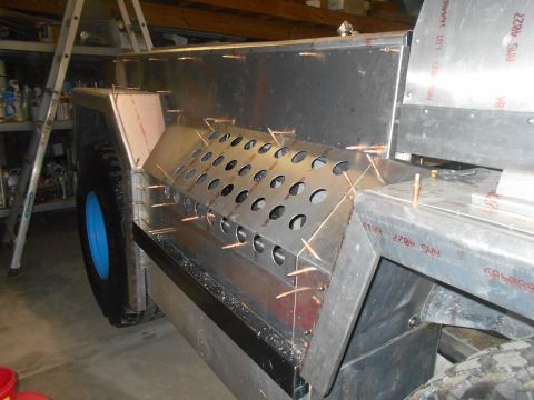 1992 Ford Bronco - A partially constructed vehicle chassis made of aluminum is shown, featuring a wheel well with a blue rim and a perforated metal panel with…