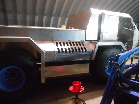 1992 Ford Bronco - A custom-built, large vehicle with a metallic body is under construction in a workshop. The vehicle features oversized tires with blue rims…