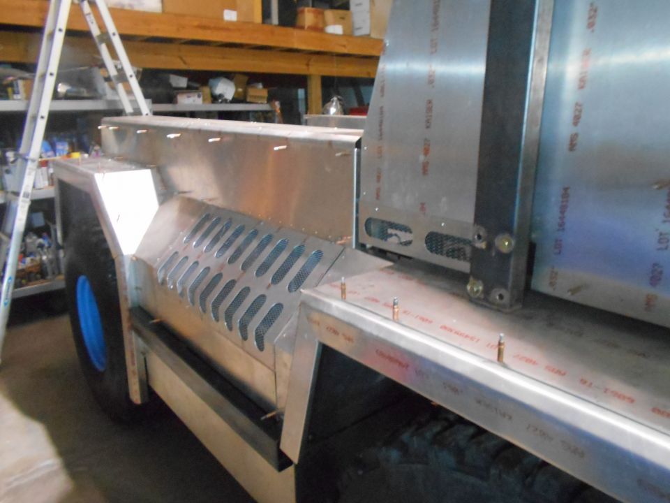 Side view of a custom aluminum vehicle with a blue wheel and vented panels.
