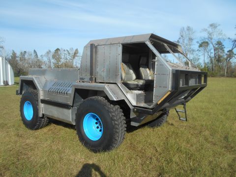1992 Ford Bronco - A custom-built, unfinished vehicle with a raw metal body sits in a grassy field under a clear blue sky. The vehicle features large off-road…