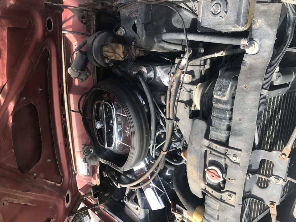 Engine bay of a classic vehicle, top-down view. Features air cleaner, radiator, hoses, and wiring.
