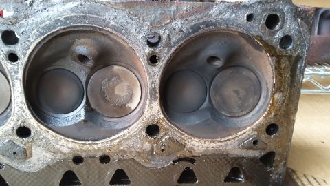 Engine cylinder head with two cylinders showing carbon buildup and wear.