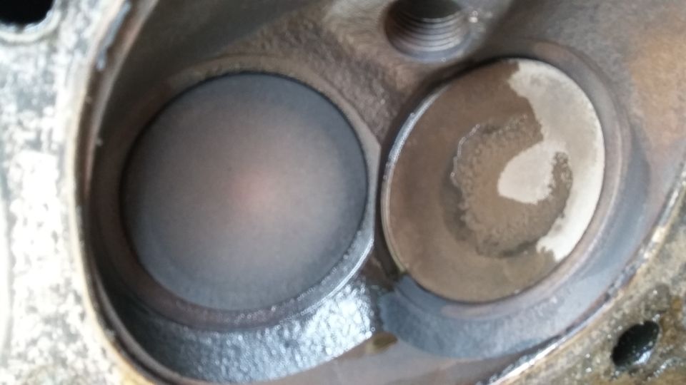 Close-up of two cylinder head combustion chambers, one clean, one with carbon buildup.