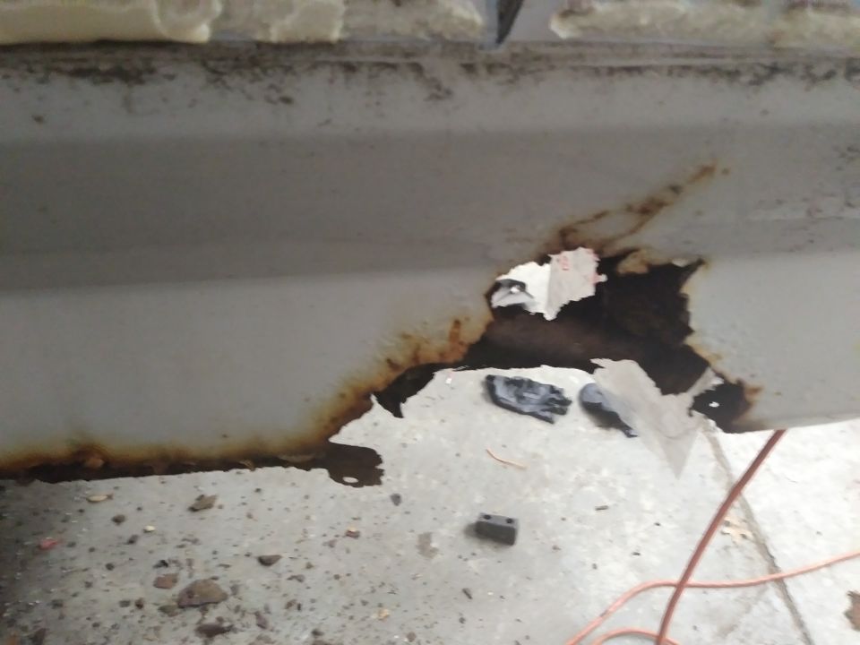 Close-up of rust and hole in vehicle body panel