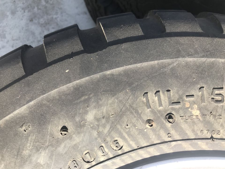 Close-up of a tire sidewall with markings 11L-15 and TUBE TYPE.