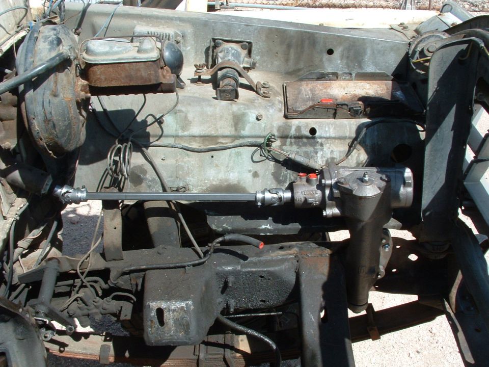 Vehicle chassis with steering box, brake master cylinder, and engine components. Some rust and grime are visible