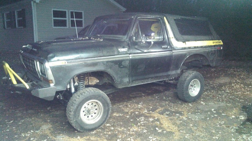 Black 1978 Ford Bronco with yellow stripe and aftermarket bumper