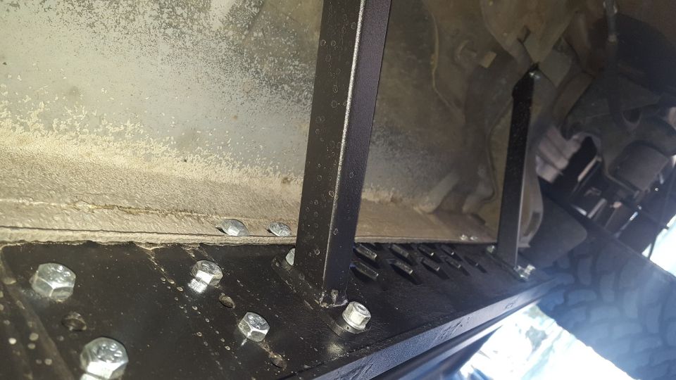 Underside view of vehicle frame with bolted-on running boards
