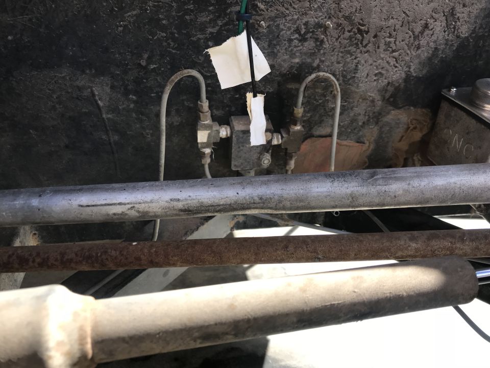 Underbody view of metal fuel lines and a valve assembly with white paper tags attached