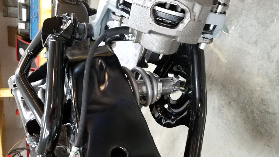 Close-up of a car's front suspension with a coilover shock and brake caliper