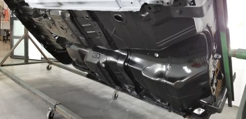 1970 Chevrolet Camaro - The underside of a vehicle chassis is shown, a black fuel tank and frame components, mounted on a repair stand.
