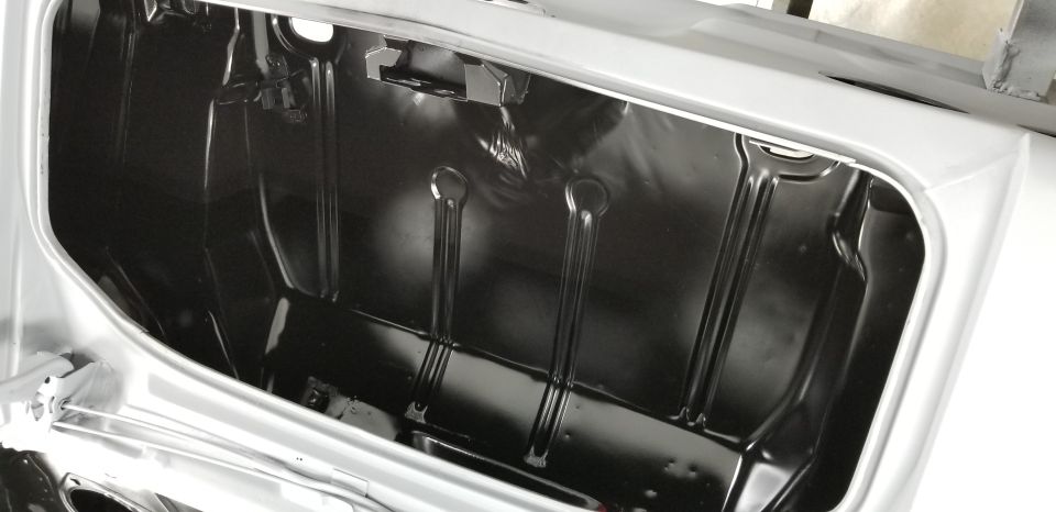 Interior of a car trunk, showing ribbed metal floor and sides painted black