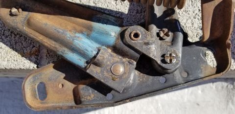 1970 Chevrolet Camaro - Close-up of a corroded vehicle hood hinge, showing mechanical components and wear.