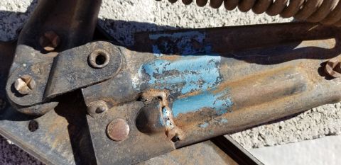 1970 Chevrolet Camaro - Close-up of a heavily rusted metal component, possibly from a vehicle, showing remnants of blue paint and a coiled spring.