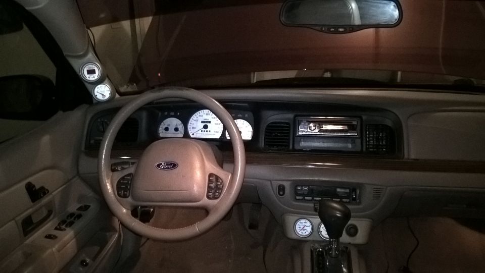 Dashboard of a 2004 Ford Crown Victoria with aftermarket gauges and a Ford steering wheel