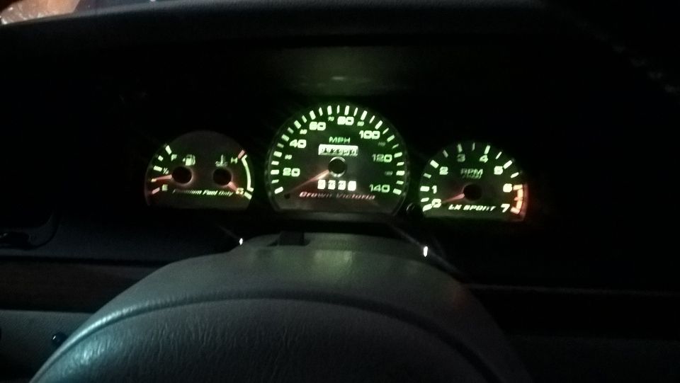 Dashboard gauges of a 2004 Ford Crown Victoria showing illuminated speedometer, tachometer, and fuel/temp gauges
