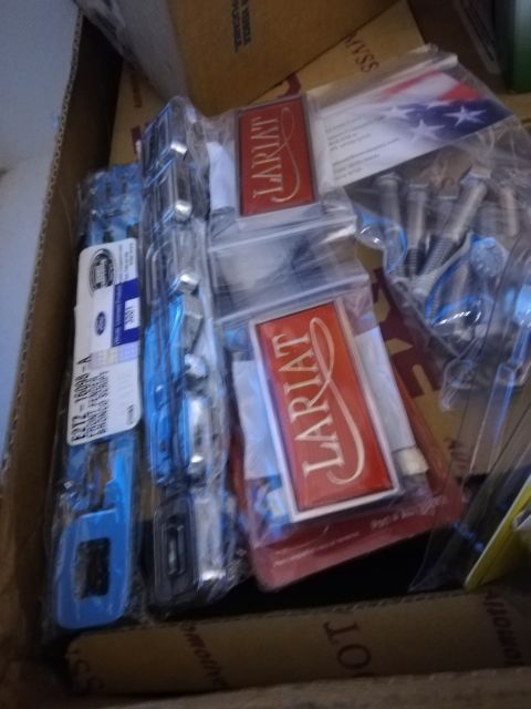 1996 Ford Bronco - Box of Ford Lariat emblems and assorted vehicle parts.