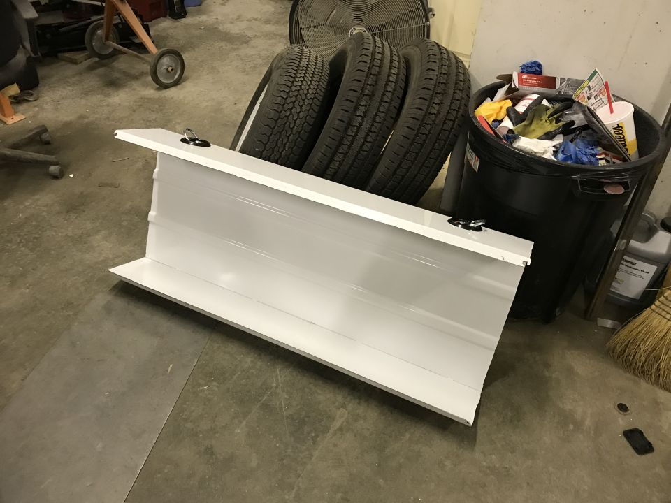 white truck tailgate with latches, tires and trash can in background