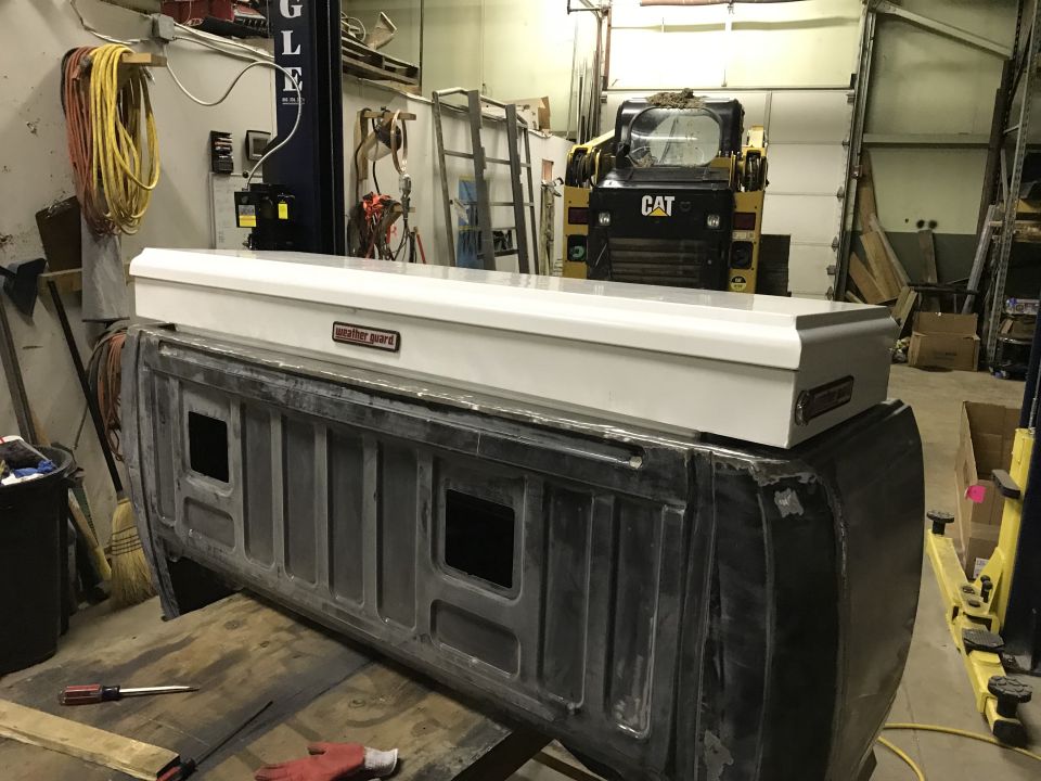 Truck bed with white Weather Guard toolbox. CAT loader in background