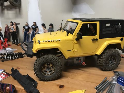 1989 Ford Bronco - Remote control Jeep Wrangler Rubicon model on a wooden surface with various accessories.