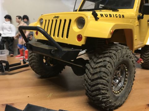 1989 Ford Bronco - A close-up view of a yellow toy Jeep Wrangler Rubicon, oversized tires and a prominent front bumper.